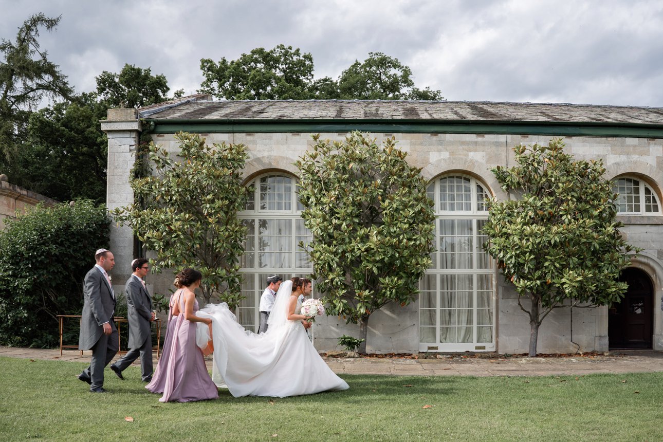A bride walks across the lawn at Stapleford Park after her Jewish wedding ceremony. 