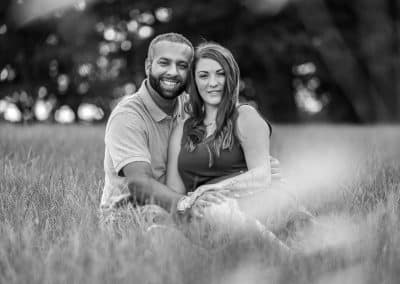 black-and-white-photo-of engaged-couple-sitting-in-long-grass