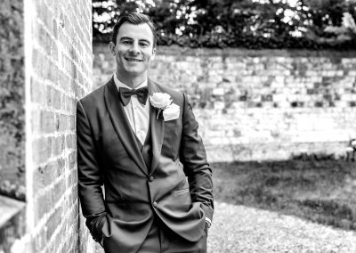 groom-leaning-against-wall-in-black-and-white-portrait