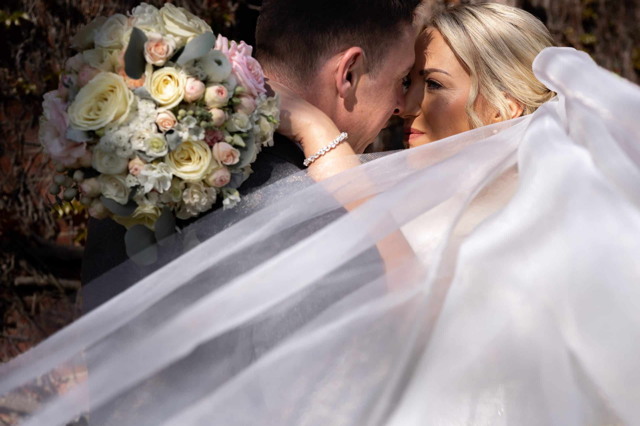 bridal-couple-in-a-hug-under-the-white-veil-at-bedford-school-chapel