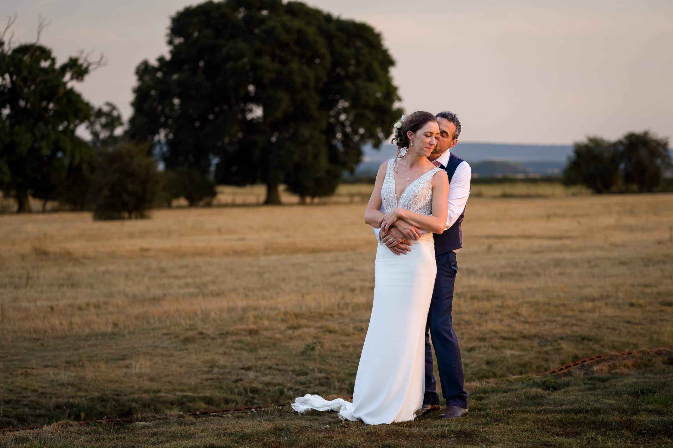 bride-and-groom-holding-each-other-in-grass-field
